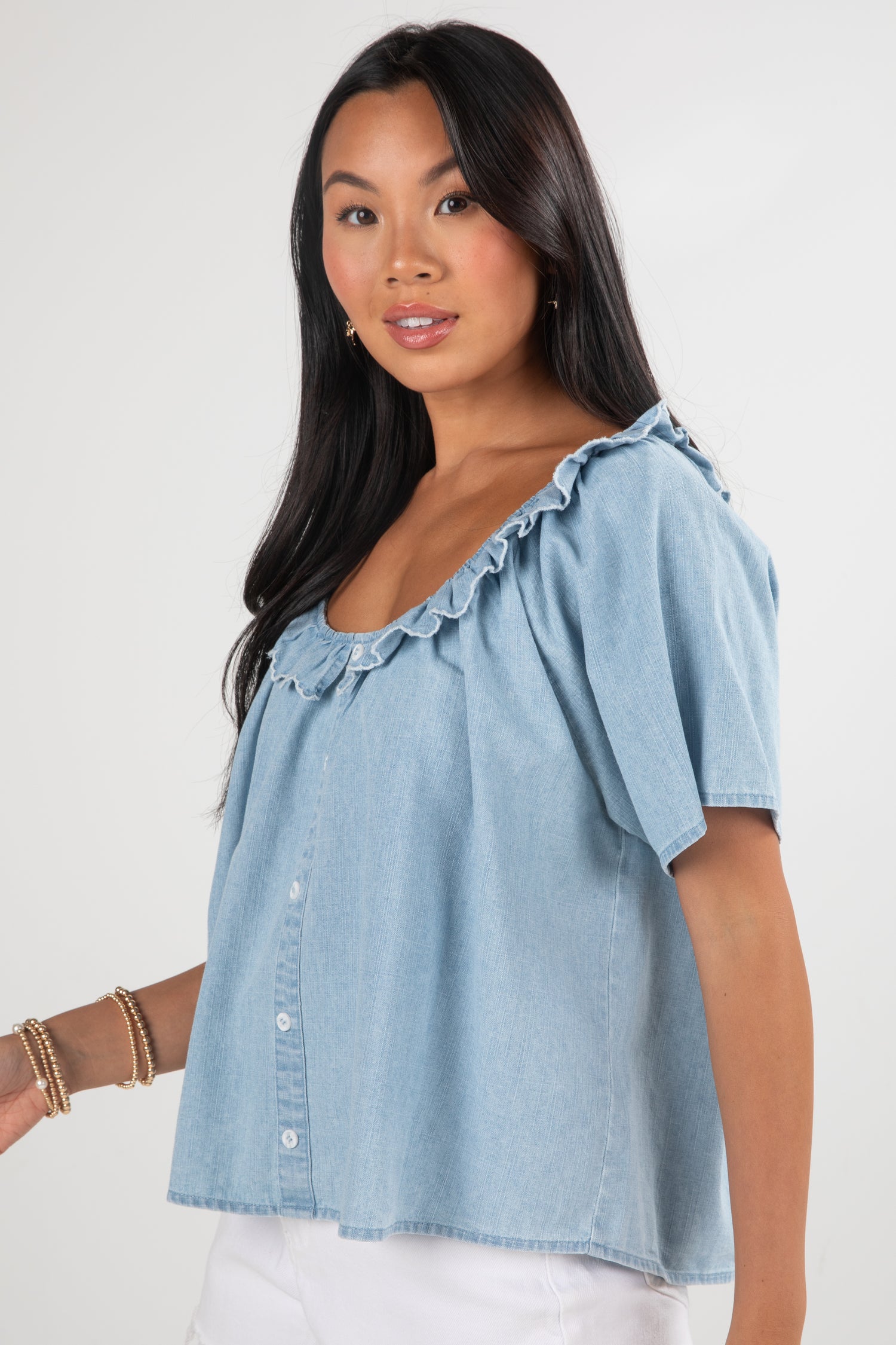 Woman wearing a light blue denim top on a white background