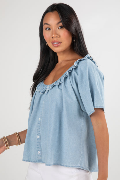 Woman wearing a light blue denim top on a white background