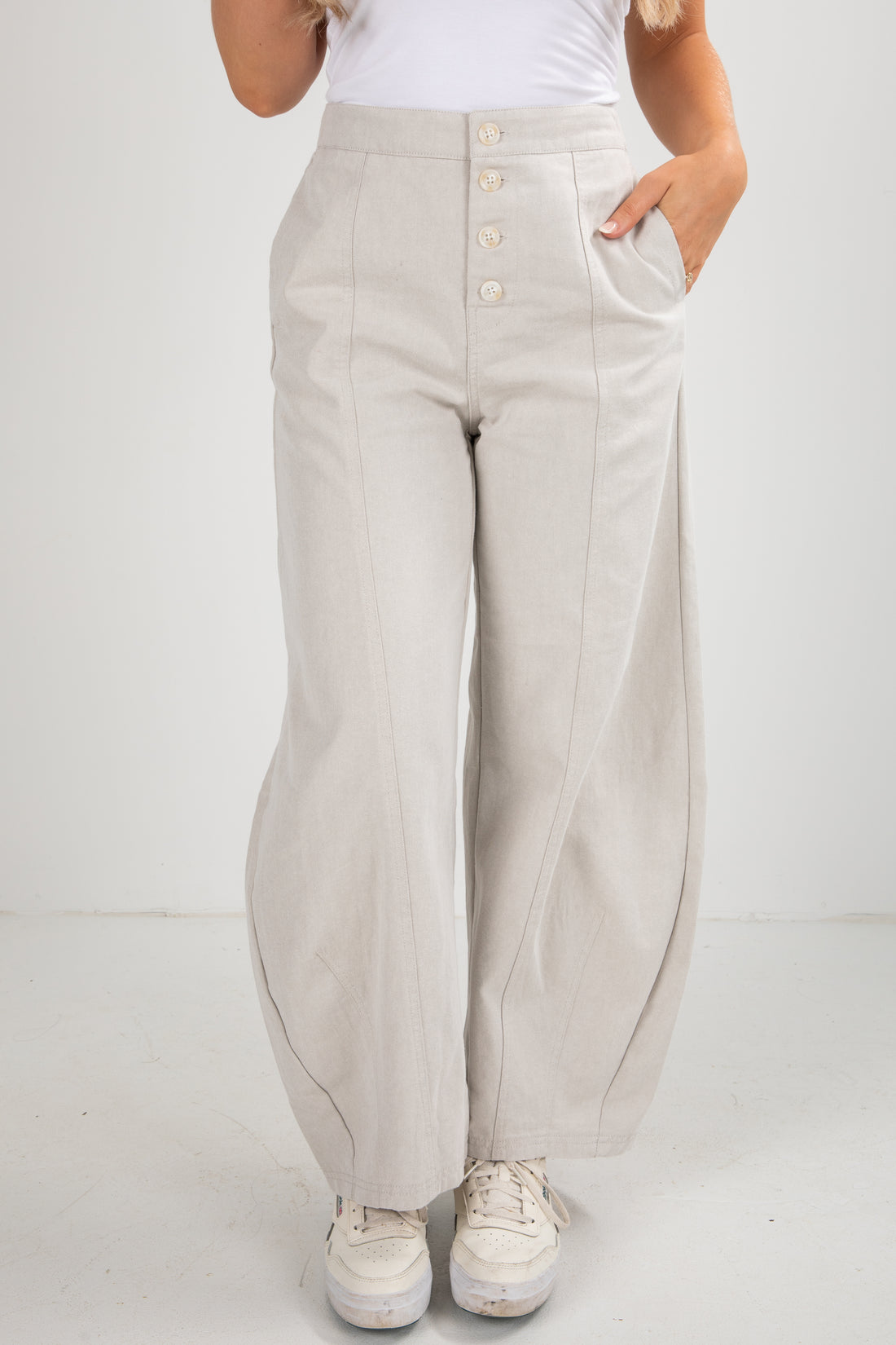 Person wearing beige wide-leg pants with a white background