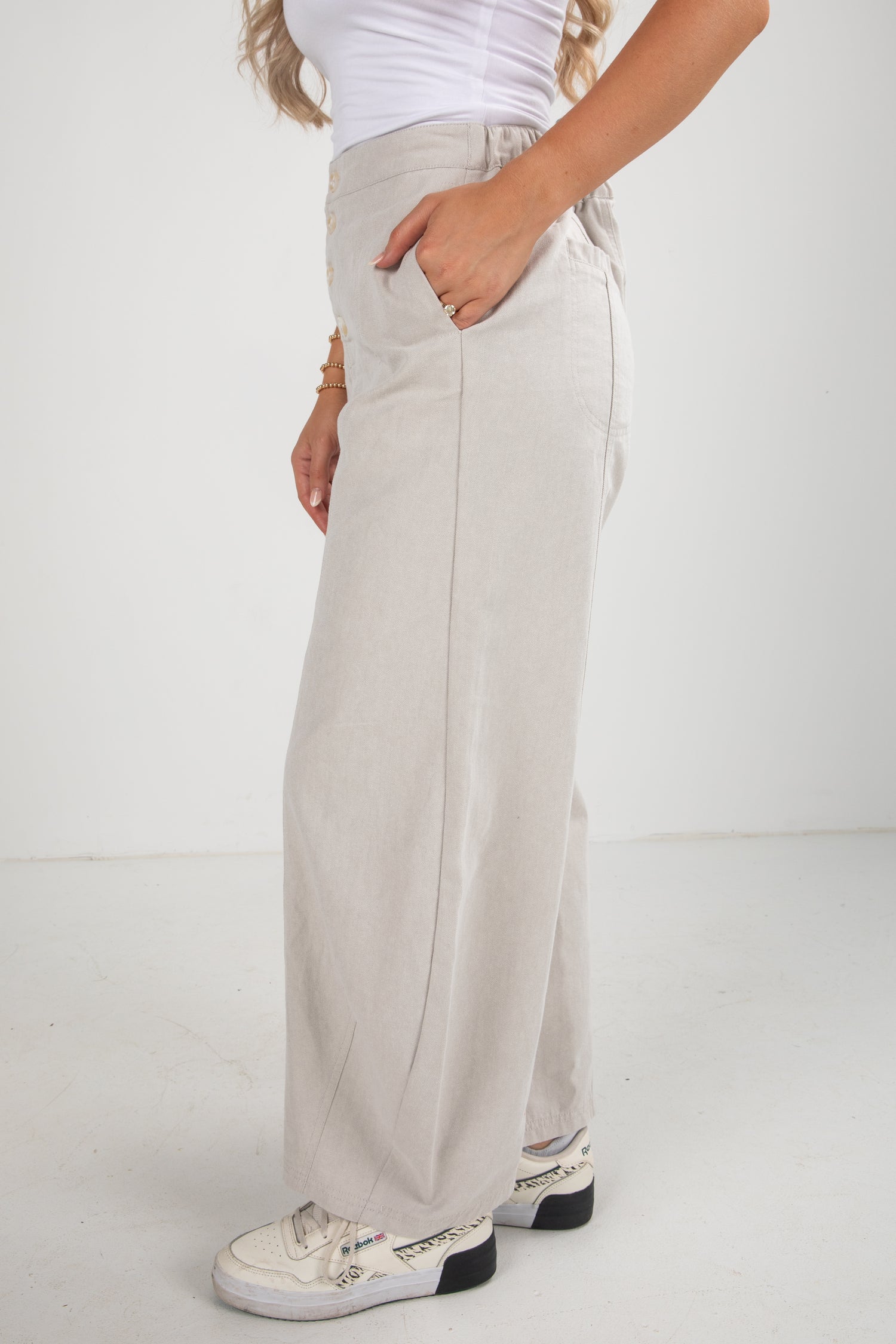 Person wearing light gray wide-leg pants with a white background