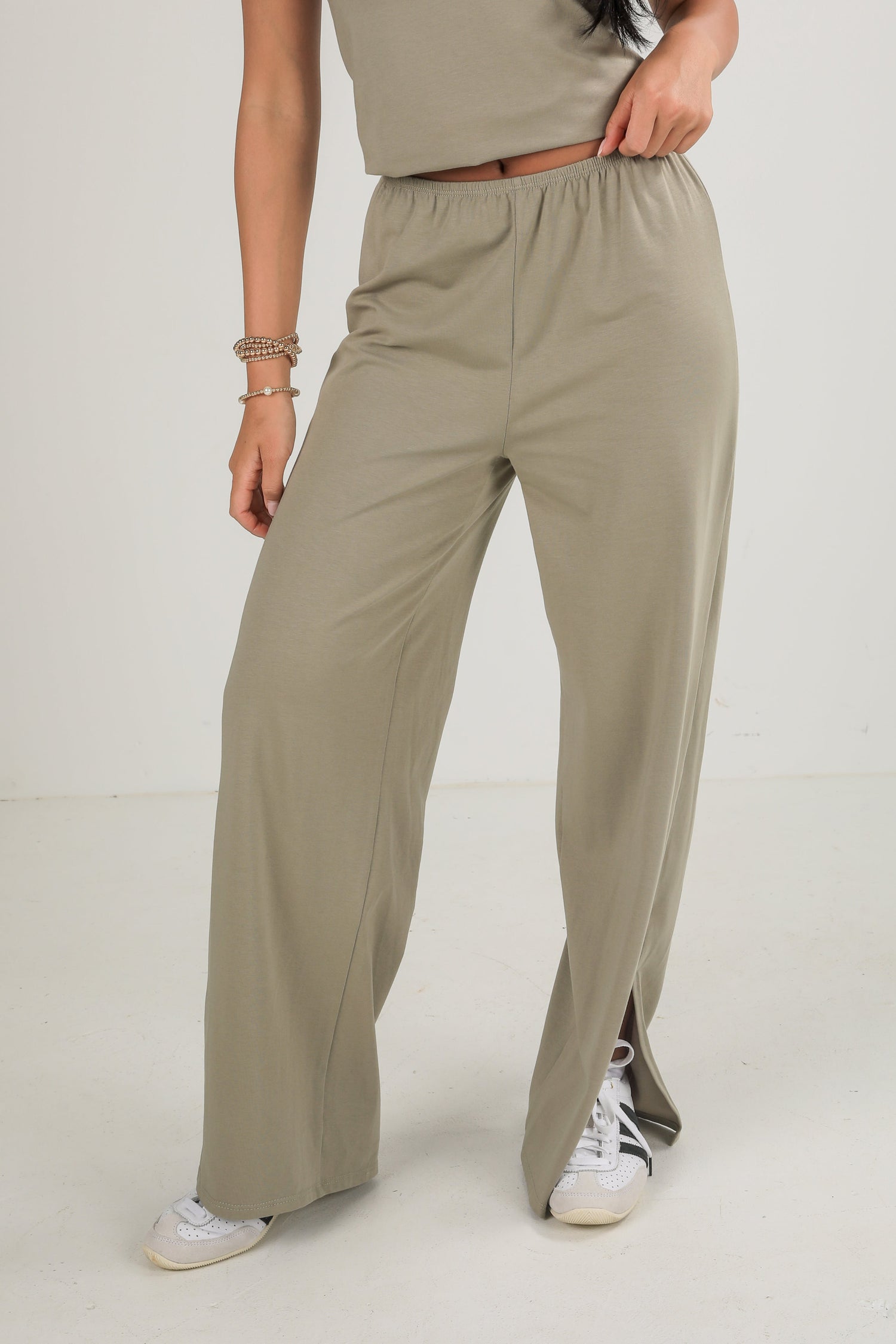 Person wearing beige wide-leg pants on a white background