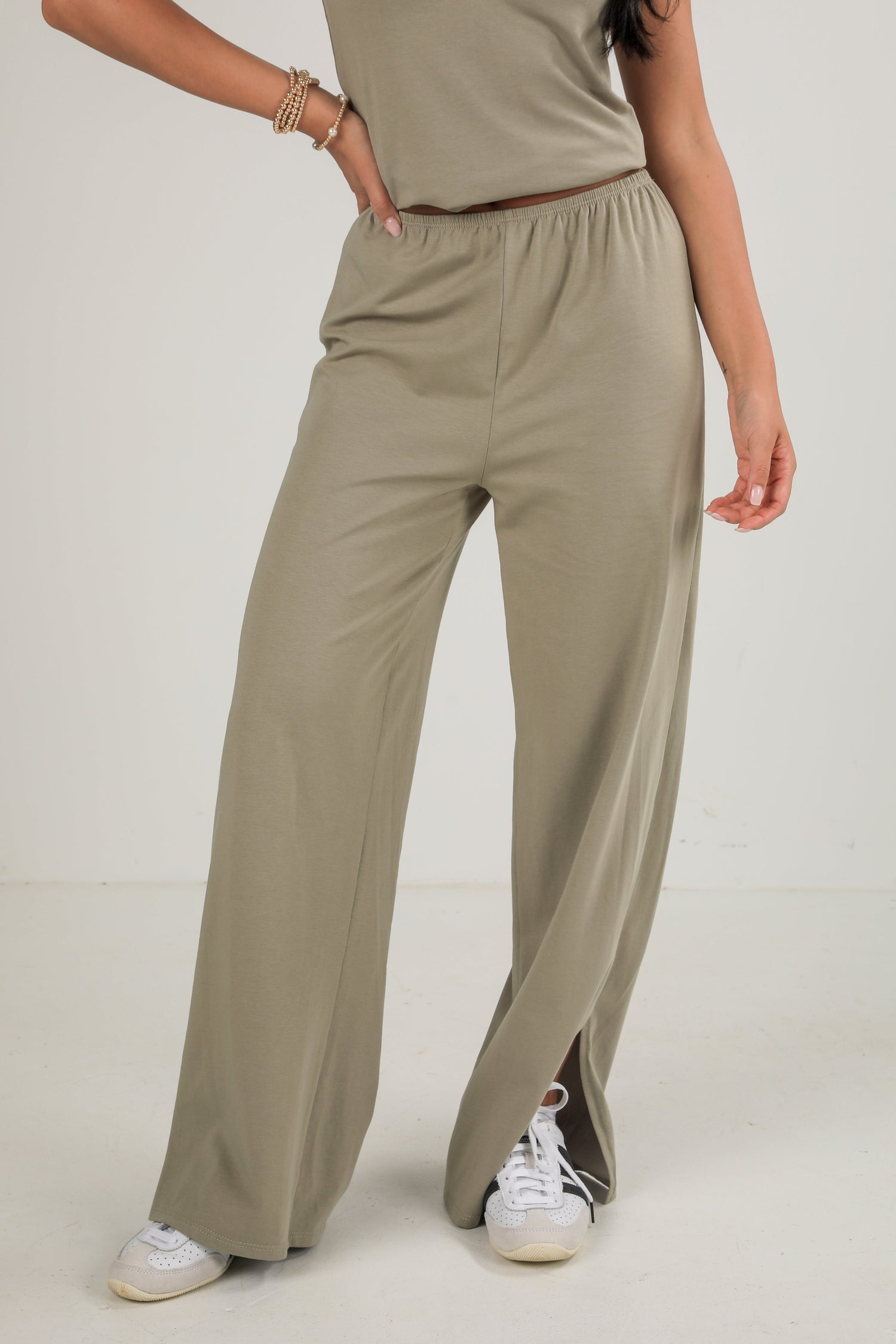 Person wearing beige pants and a matching top on a plain background