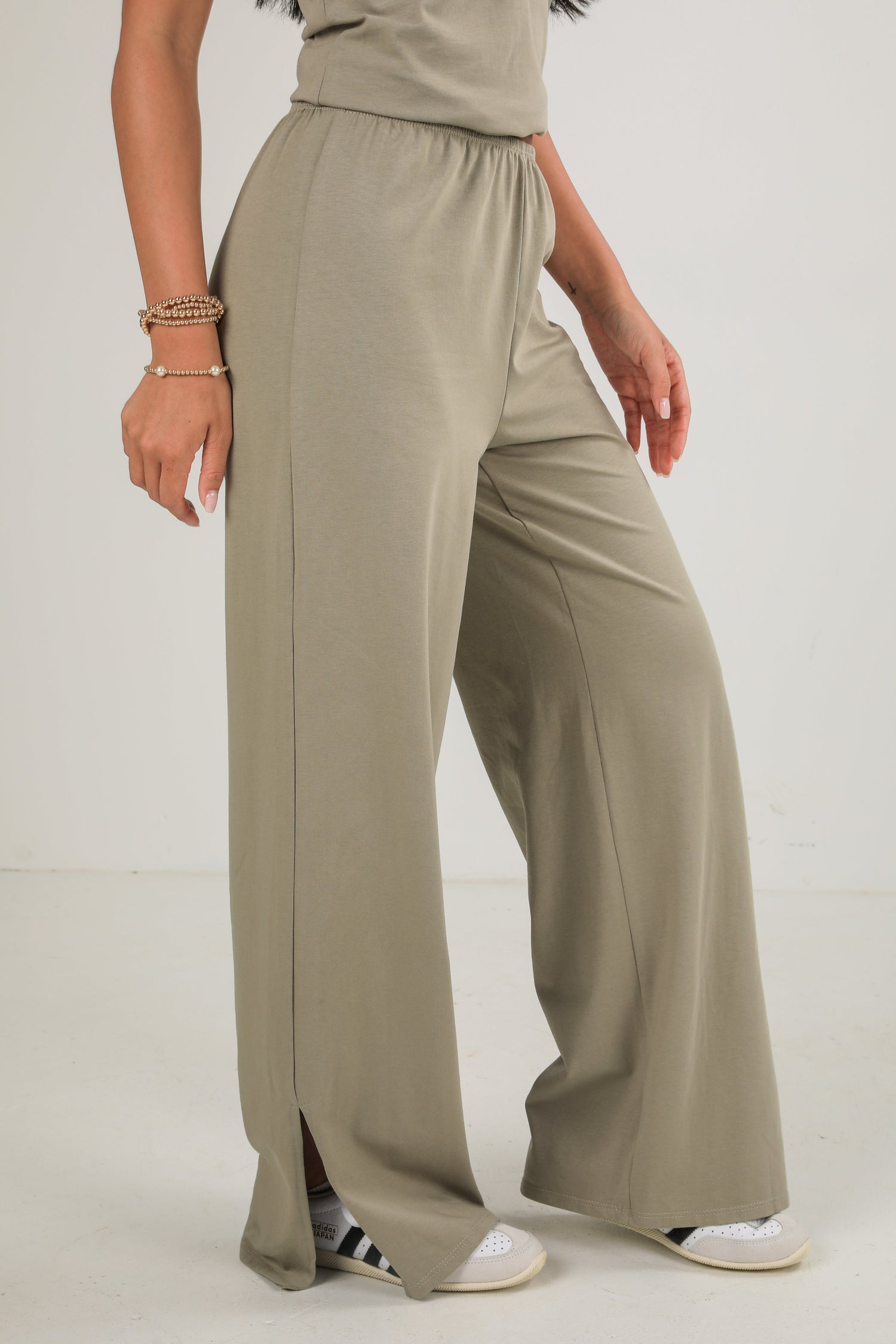 Person wearing beige wide-leg pants on a white background