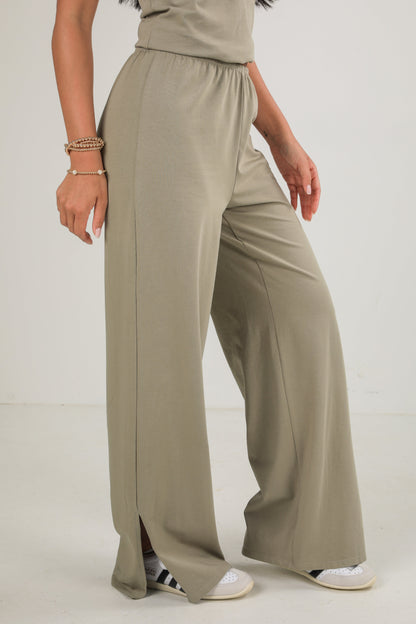 Person wearing beige wide-leg pants on a white background