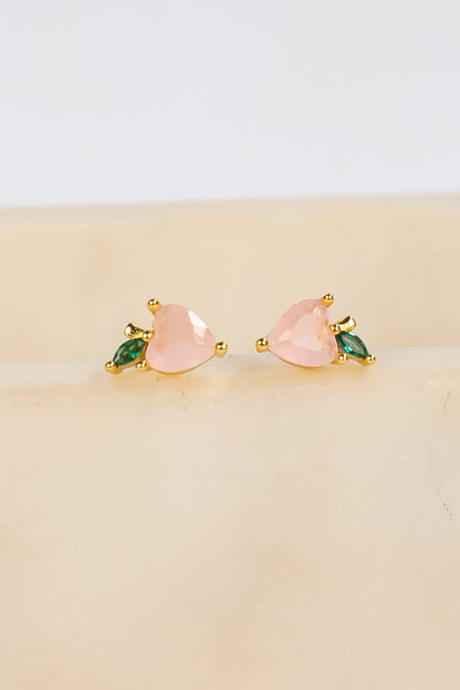 Pair of heart-shaped earrings with green accents on a beige surface.
