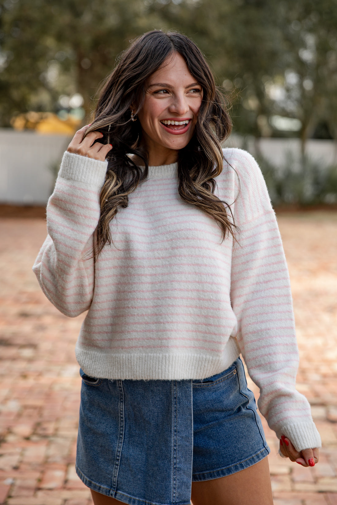 Woman wearing a white striped sweater and denim shorts outdoors