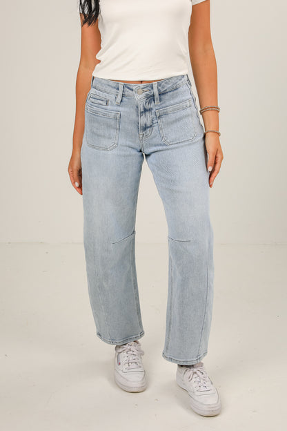 Person wearing light blue jeans and white sneakers on a plain background