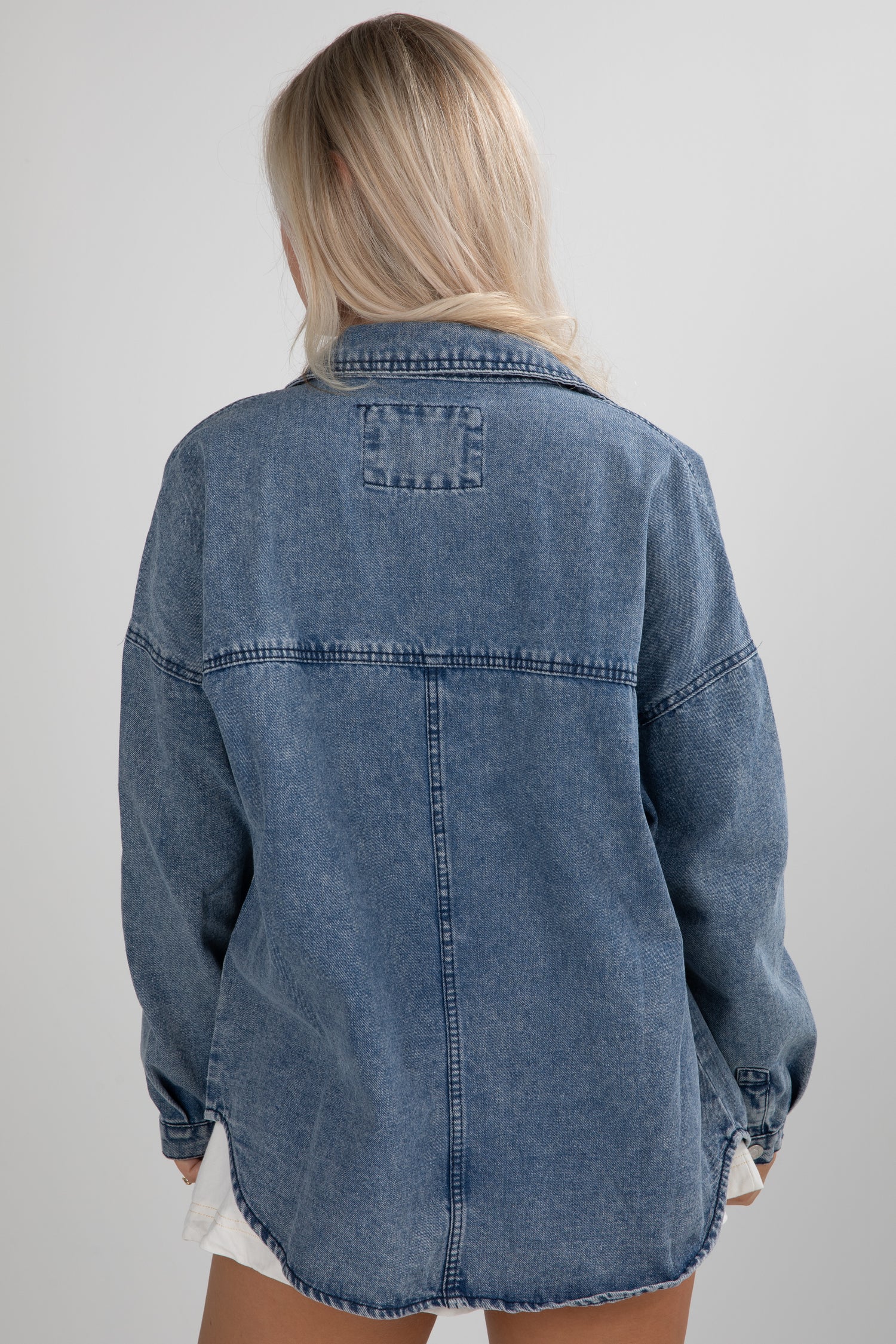 Blue denim jacket worn by a person on a plain background