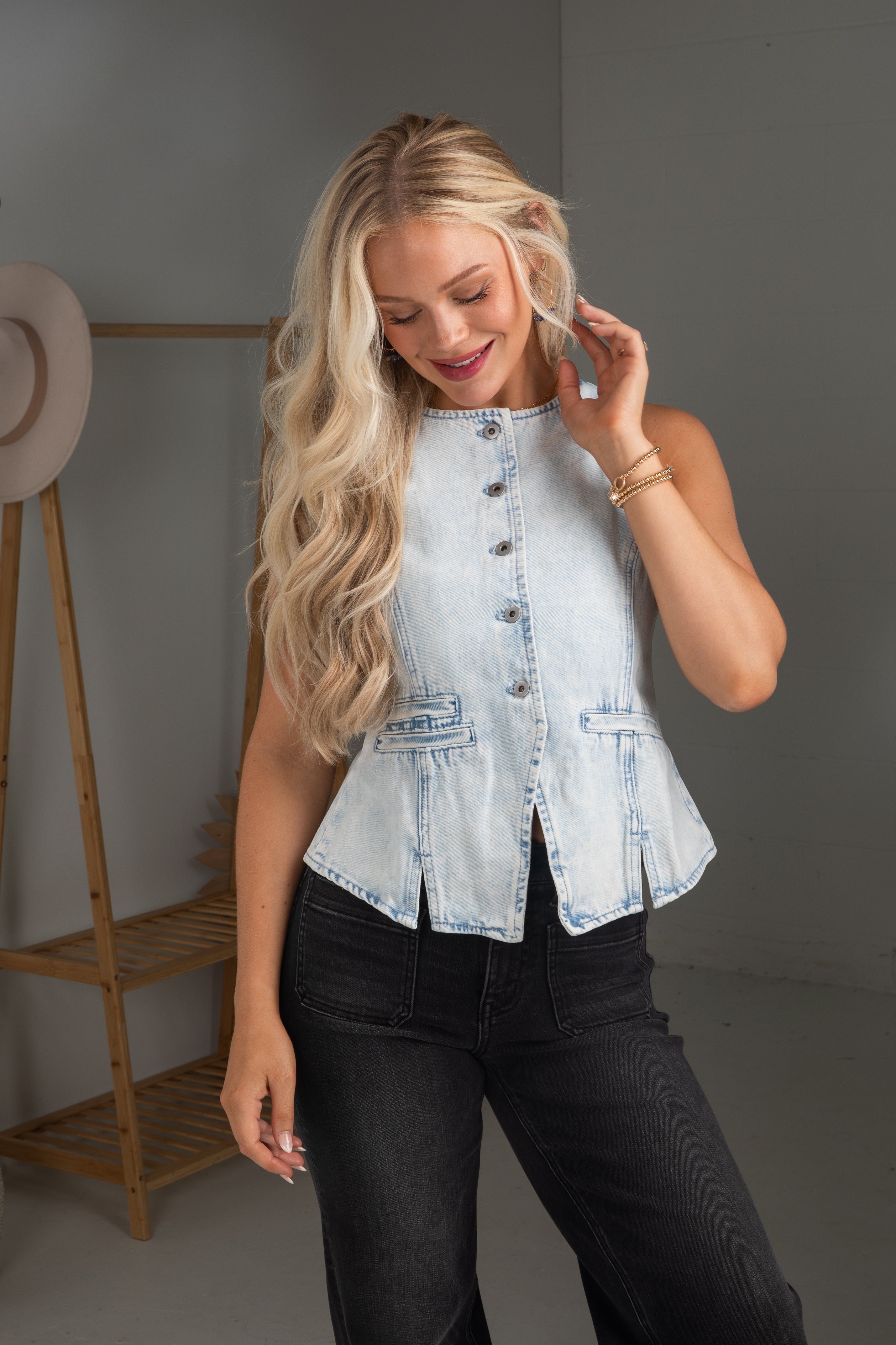 Woman wearing a light blue denim top and black pants, standing against a plain background.