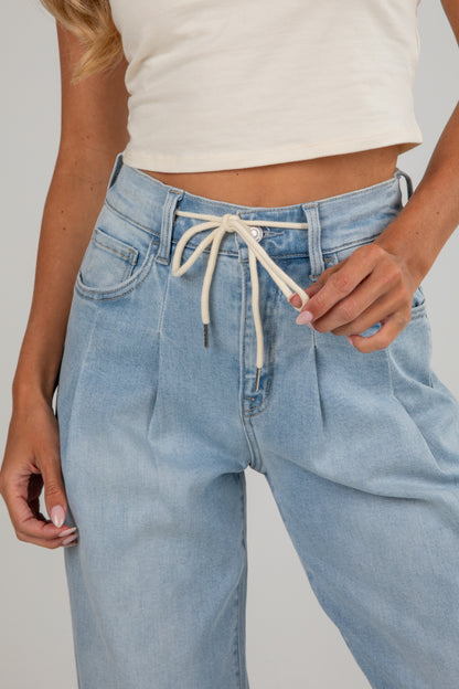 Light blue jeans with a white top on a plain background