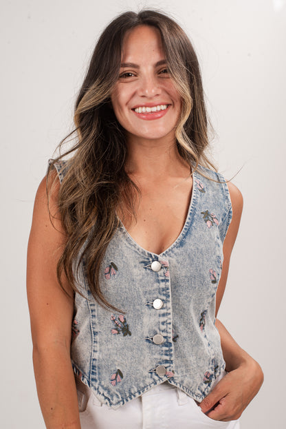 Woman wearing a denim vest with floral embroidery on a white background