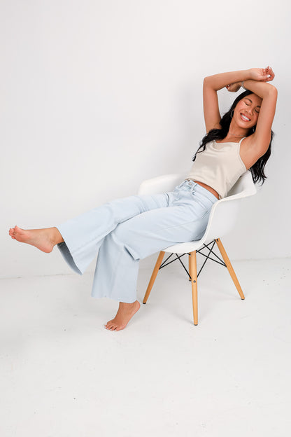 Woman sitting on a chair with her legs crossed against a white background