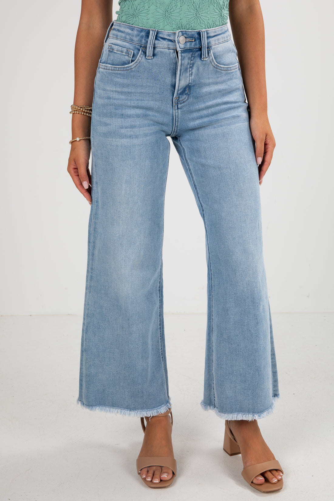 Person wearing light blue wide-leg jeans on a white background