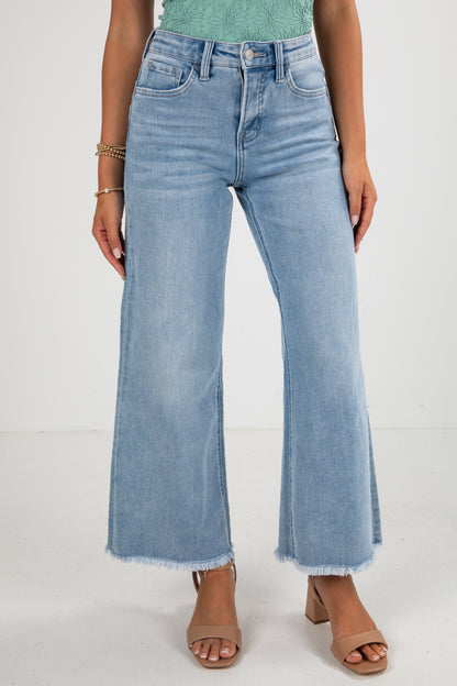 Person wearing light blue wide-leg jeans on a white background