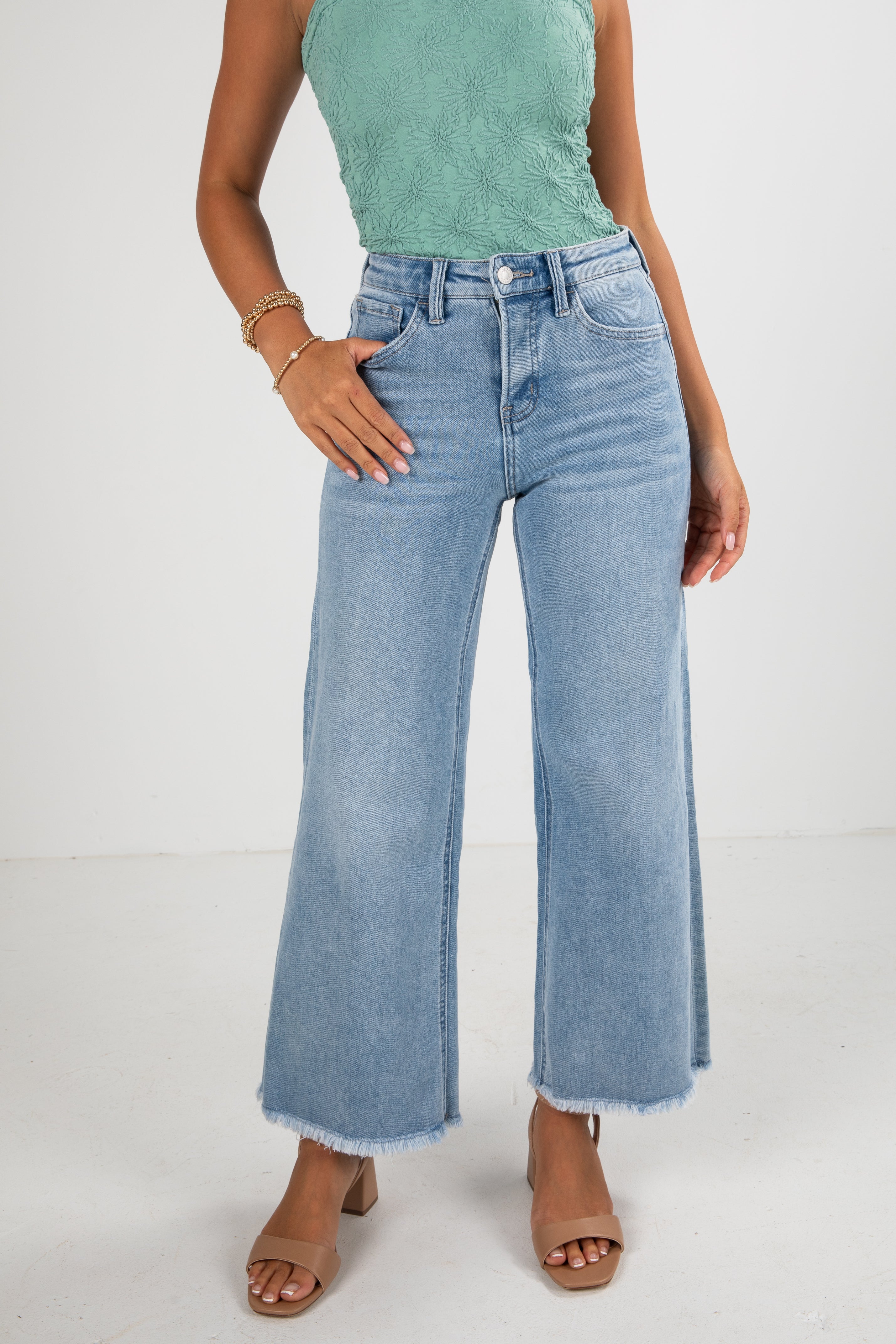 Person wearing light blue jeans and a green top on a white background