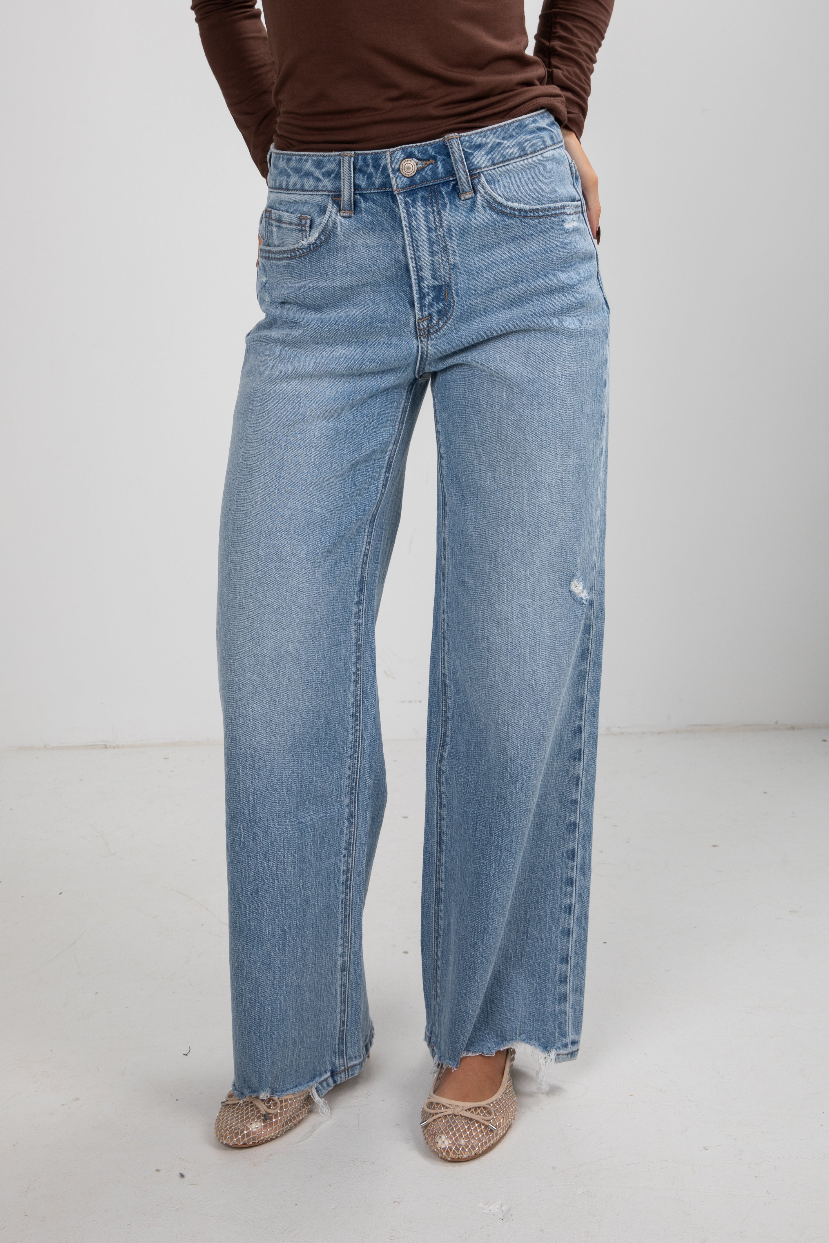 Person wearing light blue jeans on a white background