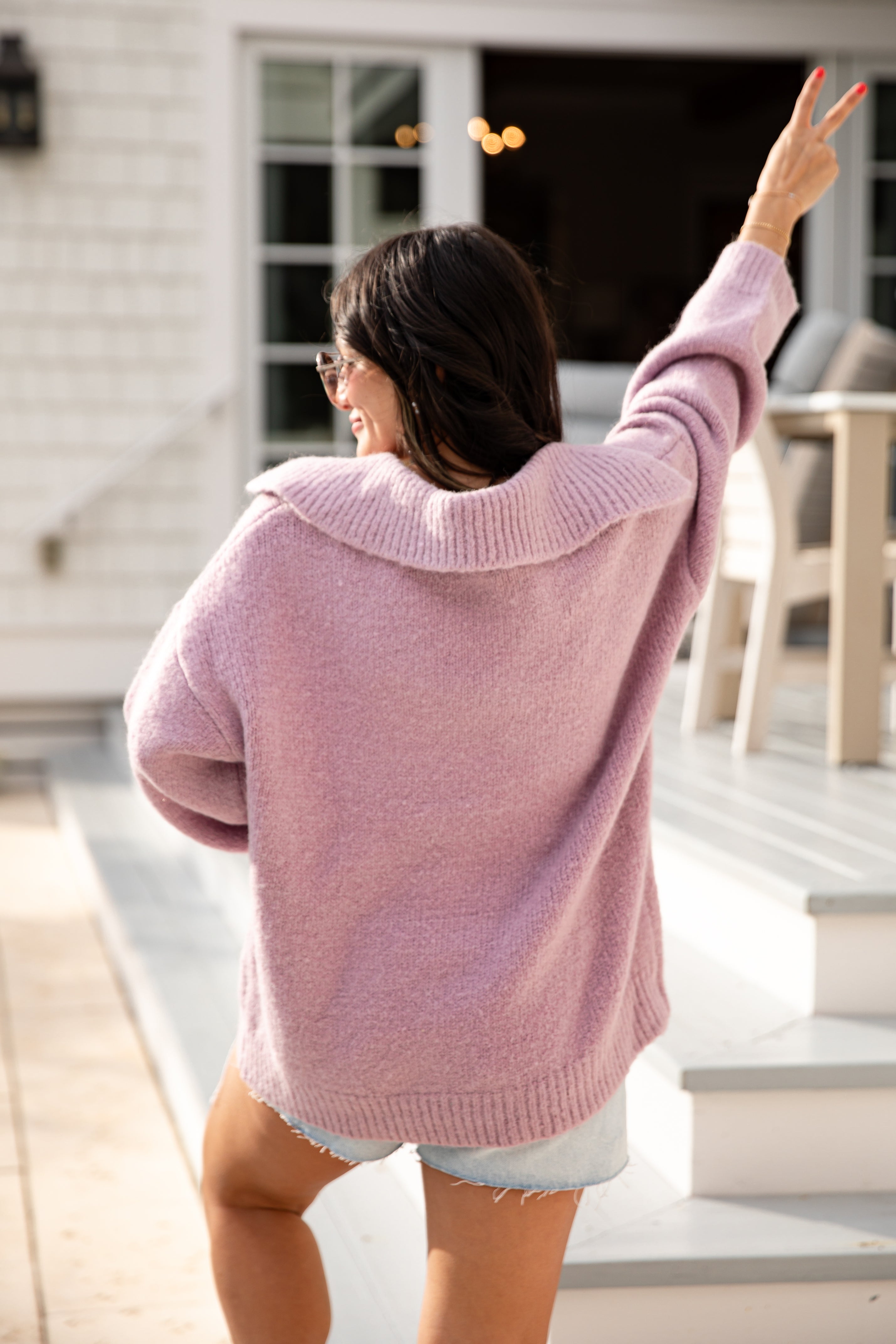 Woman wearing a pink sweater standing on a porch