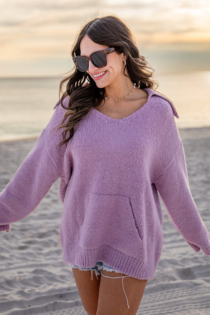 Woman wearing a purple sweater on a beach at sunset