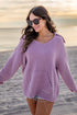 Woman wearing a purple sweater on a beach at sunset