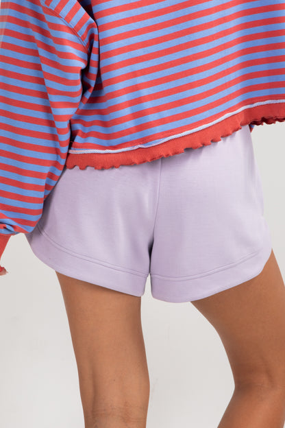 Person wearing a red and blue striped shirt and purple shorts on a light background