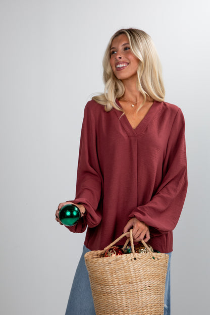 Woman holding a bottle and a woven basket against a plain background