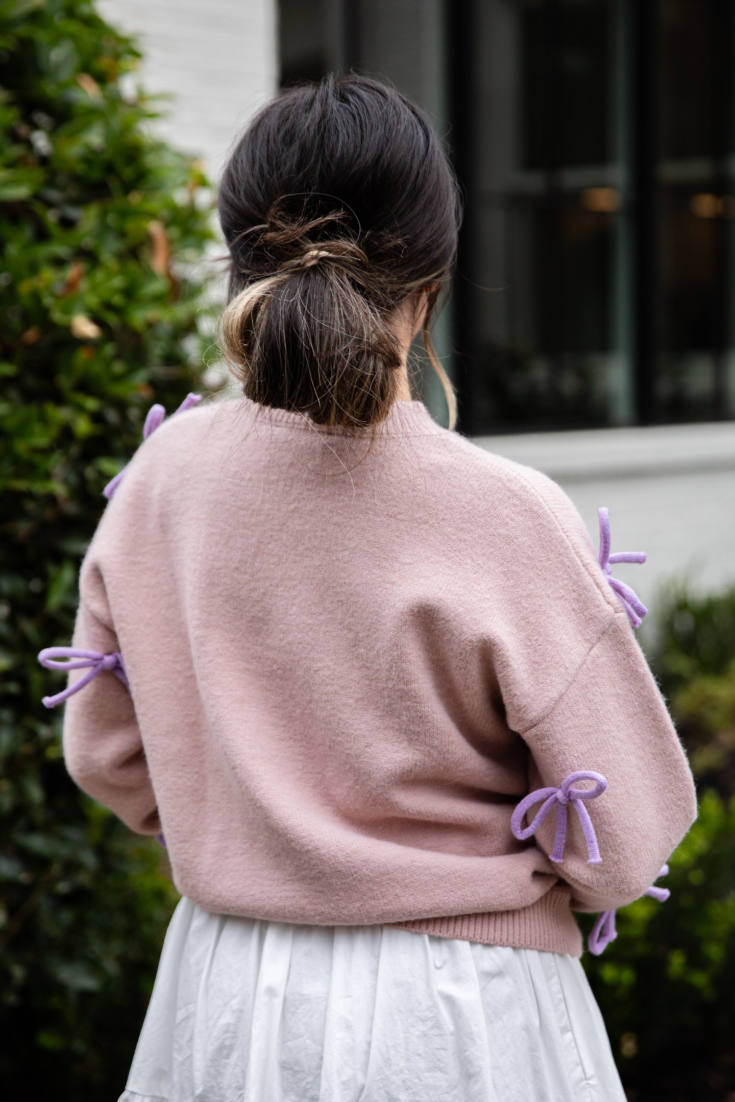 Person wearing a pink sweater with purple accents outdoors