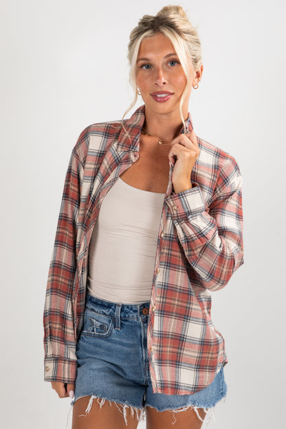 Woman wearing a plaid shirt over a tank top and denim shorts on a white background