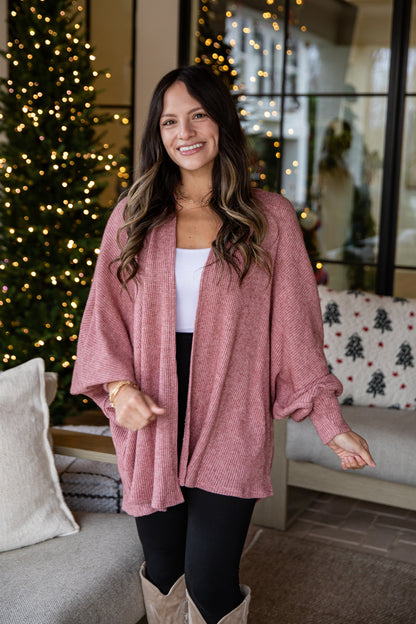 Woman in a pink cardigan standing in a living room with Christmas decorations.