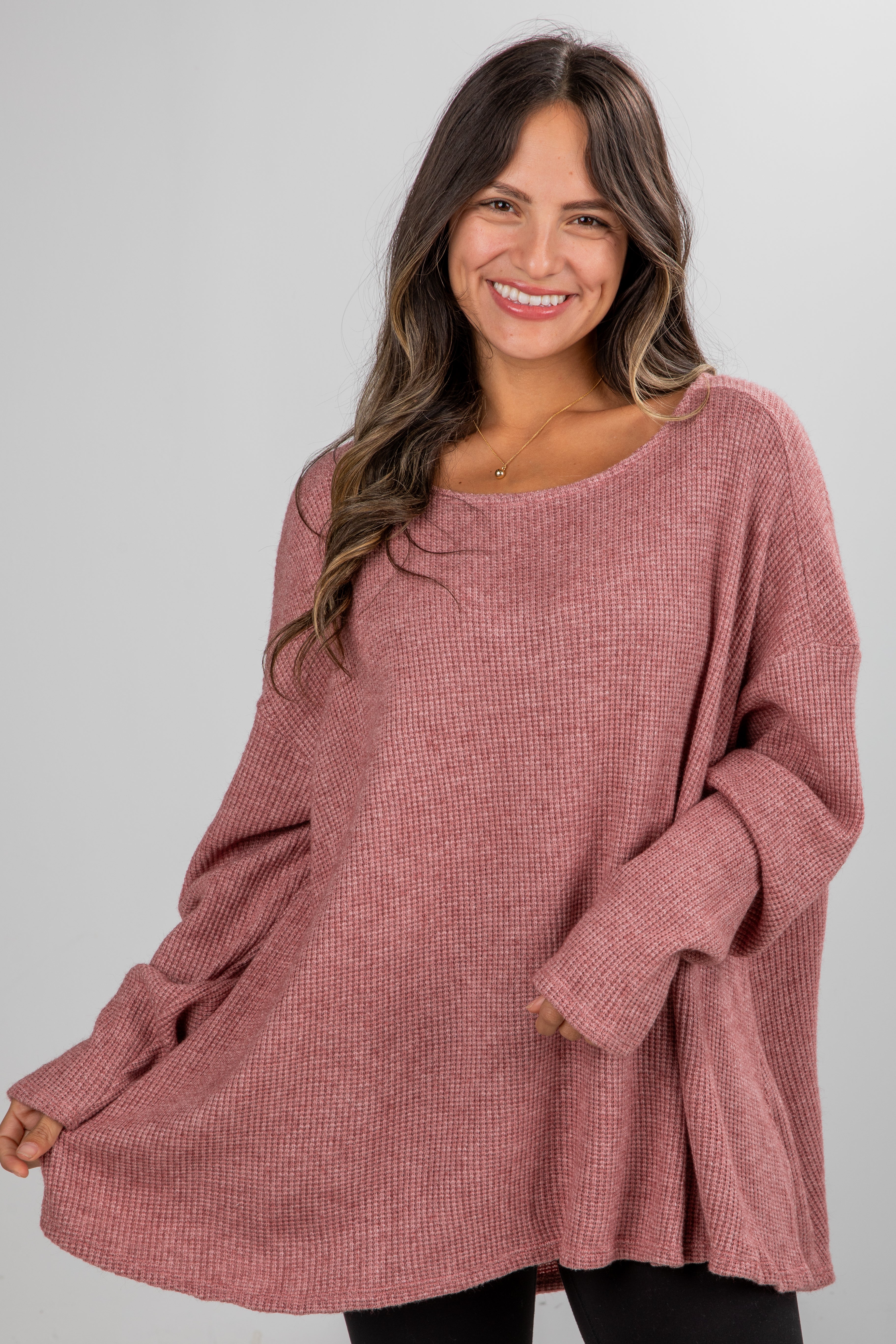 Woman wearing a pink sweater against a gray background