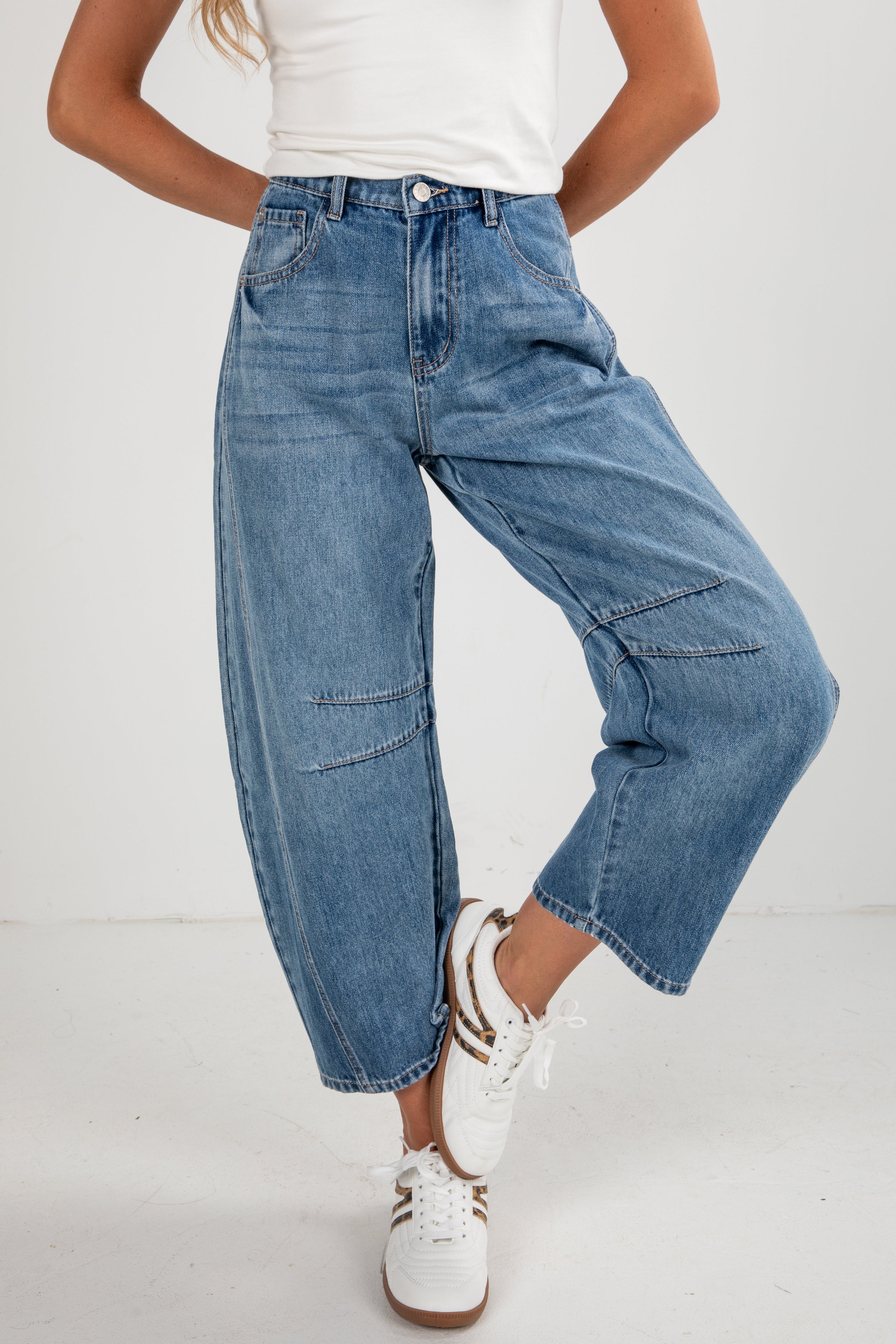 Person wearing blue jeans and white sneakers on a plain background