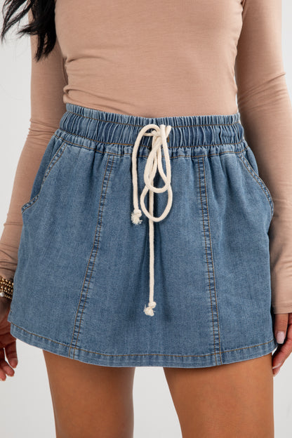 Denim skirt with drawstring waist worn by a person against a neutral background