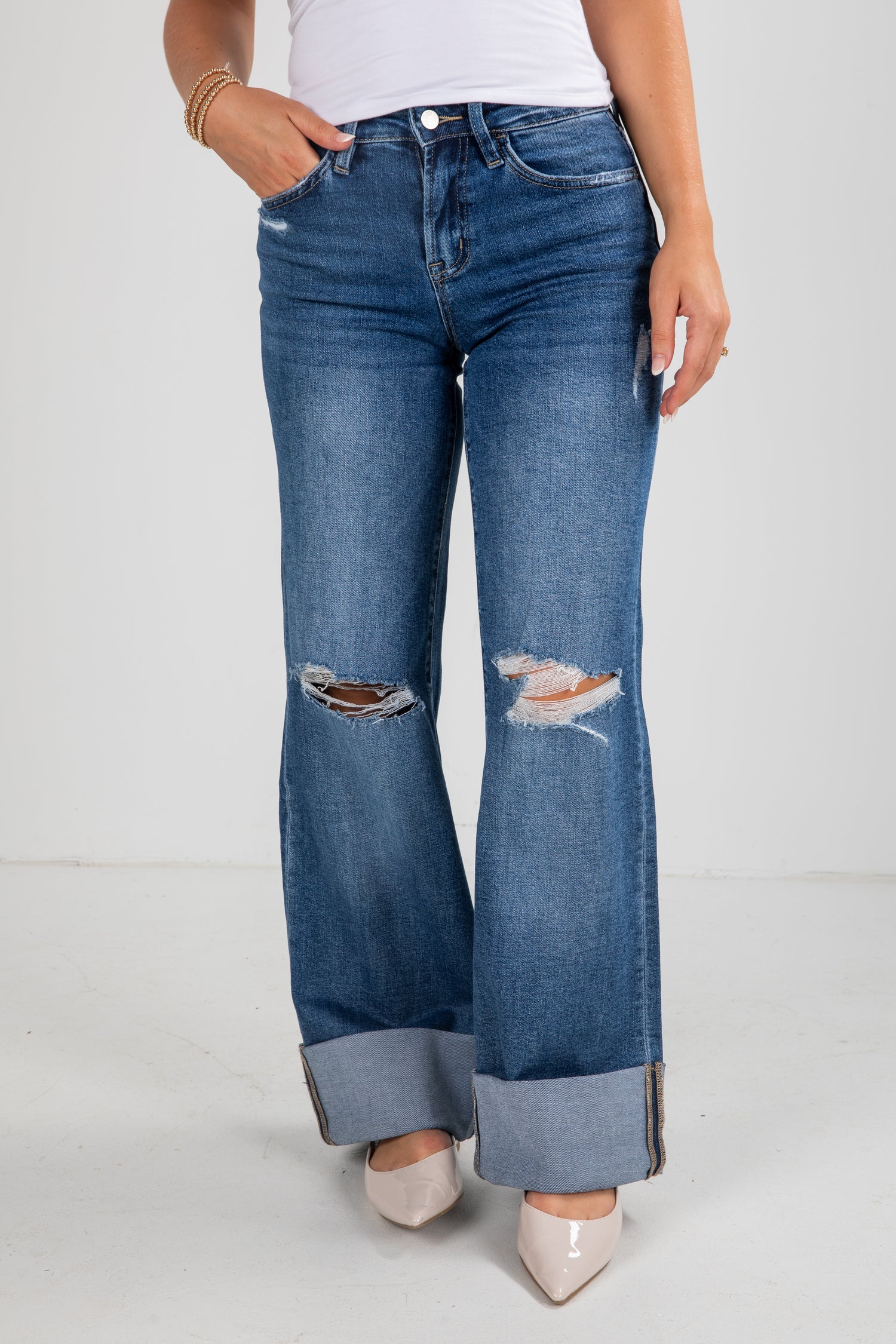 Blue jeans with a slight distressed look worn by a person on a white background