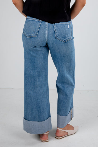 Person wearing blue wide-leg jeans on a white background
