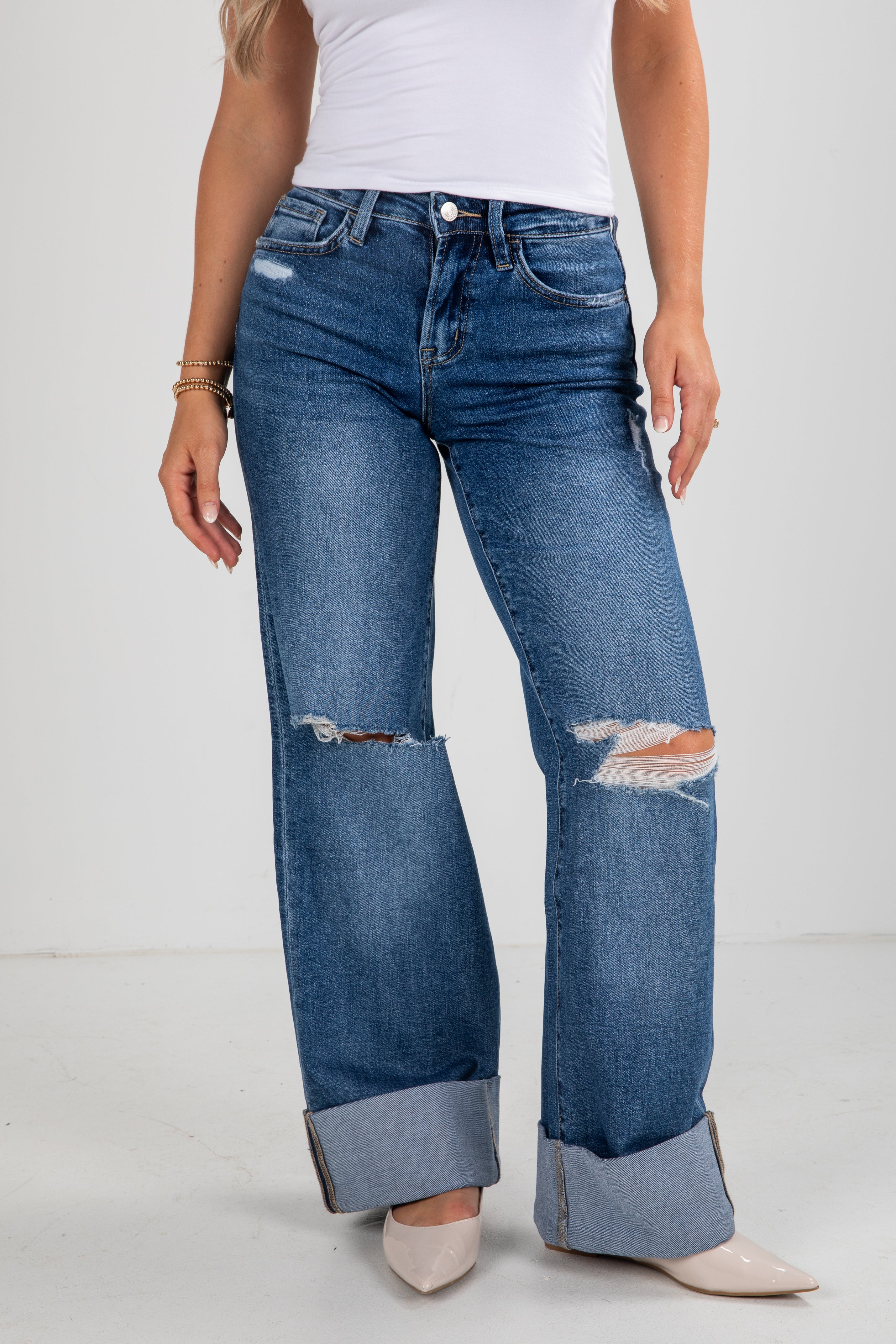 Person wearing blue distressed jeans on a white background