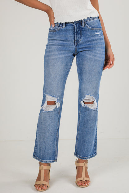 Person wearing distressed blue jeans on a white background