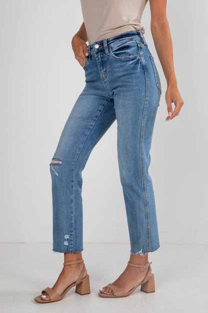 Person wearing blue jeans and beige sandals on a white background