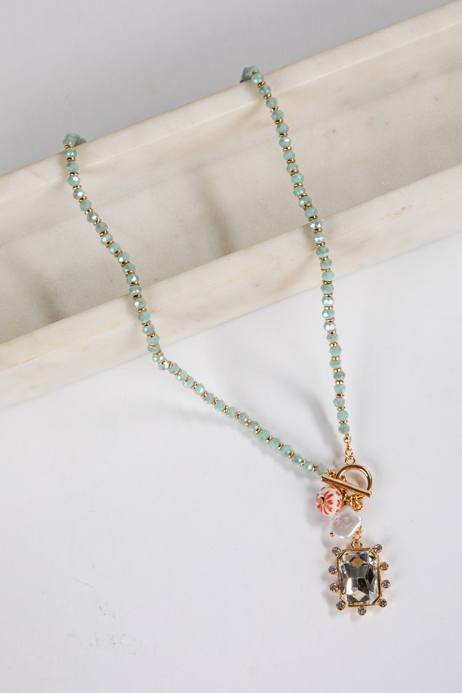Necklace with gemstone pendant on a marble surface