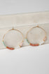 Gold hoop earrings with colorful beads on a marble surface