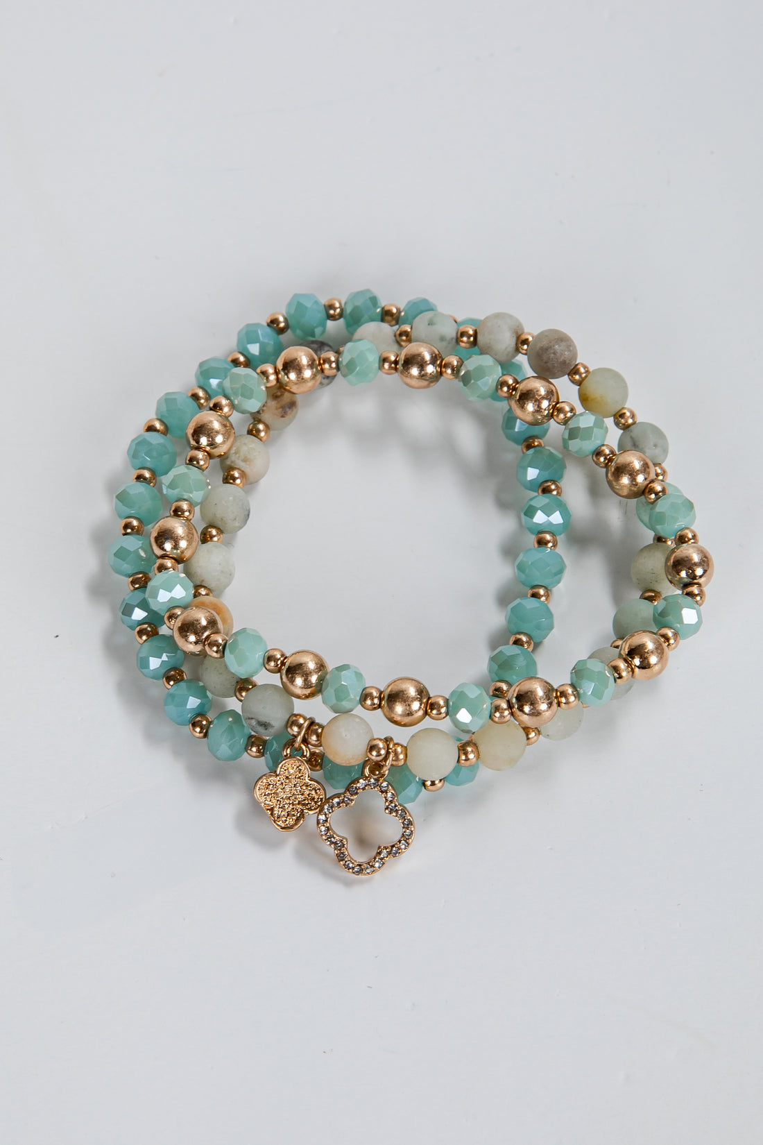 Set of turquoise and gold beaded bracelets on a light gray background