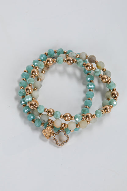Set of turquoise and gold beaded bracelets on a light gray background