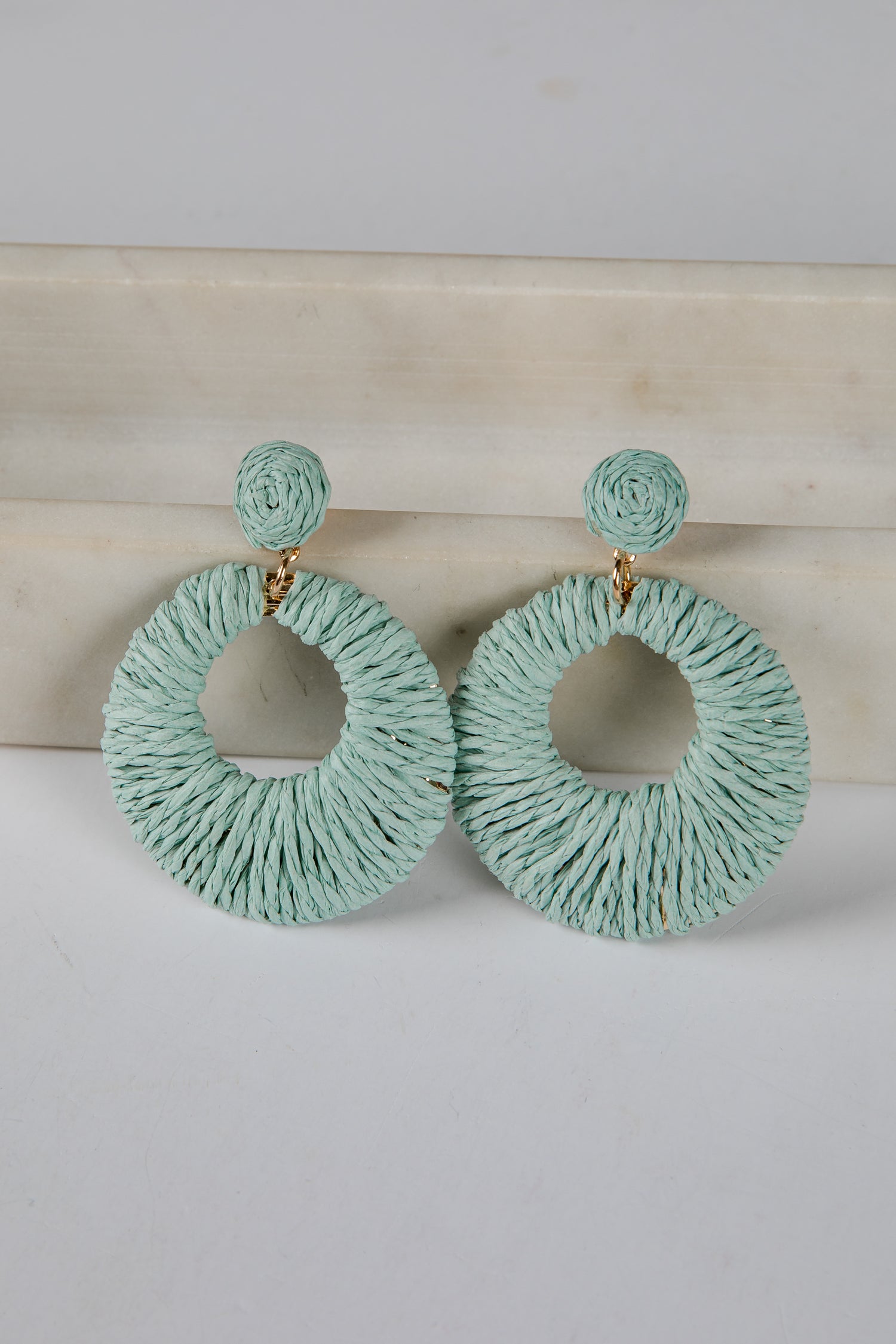 Pair of light blue hoop earrings on a white surface with a beige background