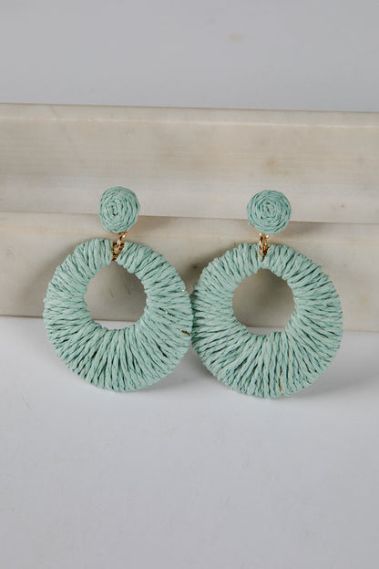 Pair of light blue hoop earrings on a white surface with a beige background