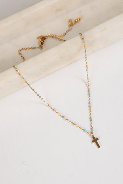 Gold necklace with a cross pendant on a white surface
