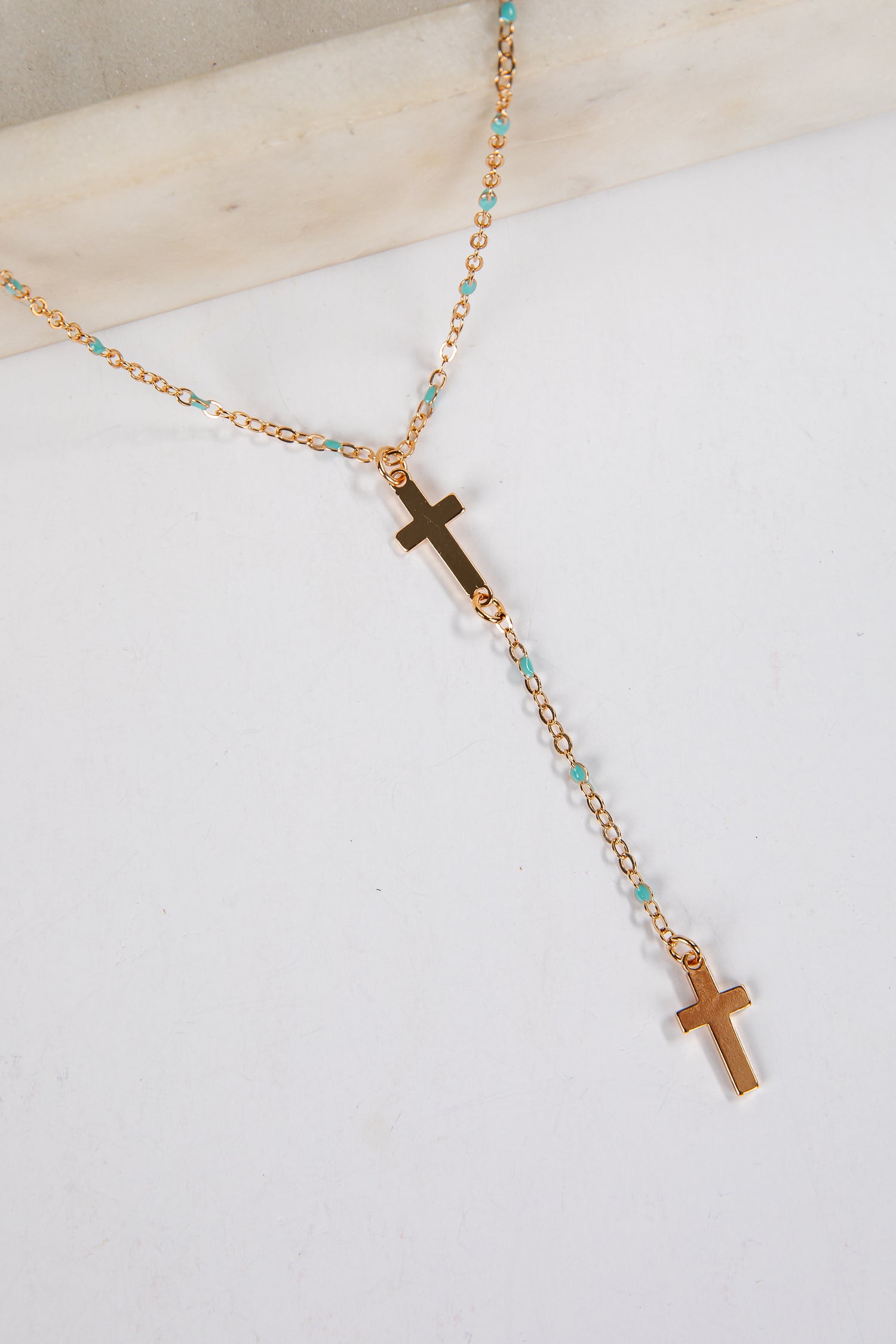 Necklace with gold crosses and turquoise beads on a white background