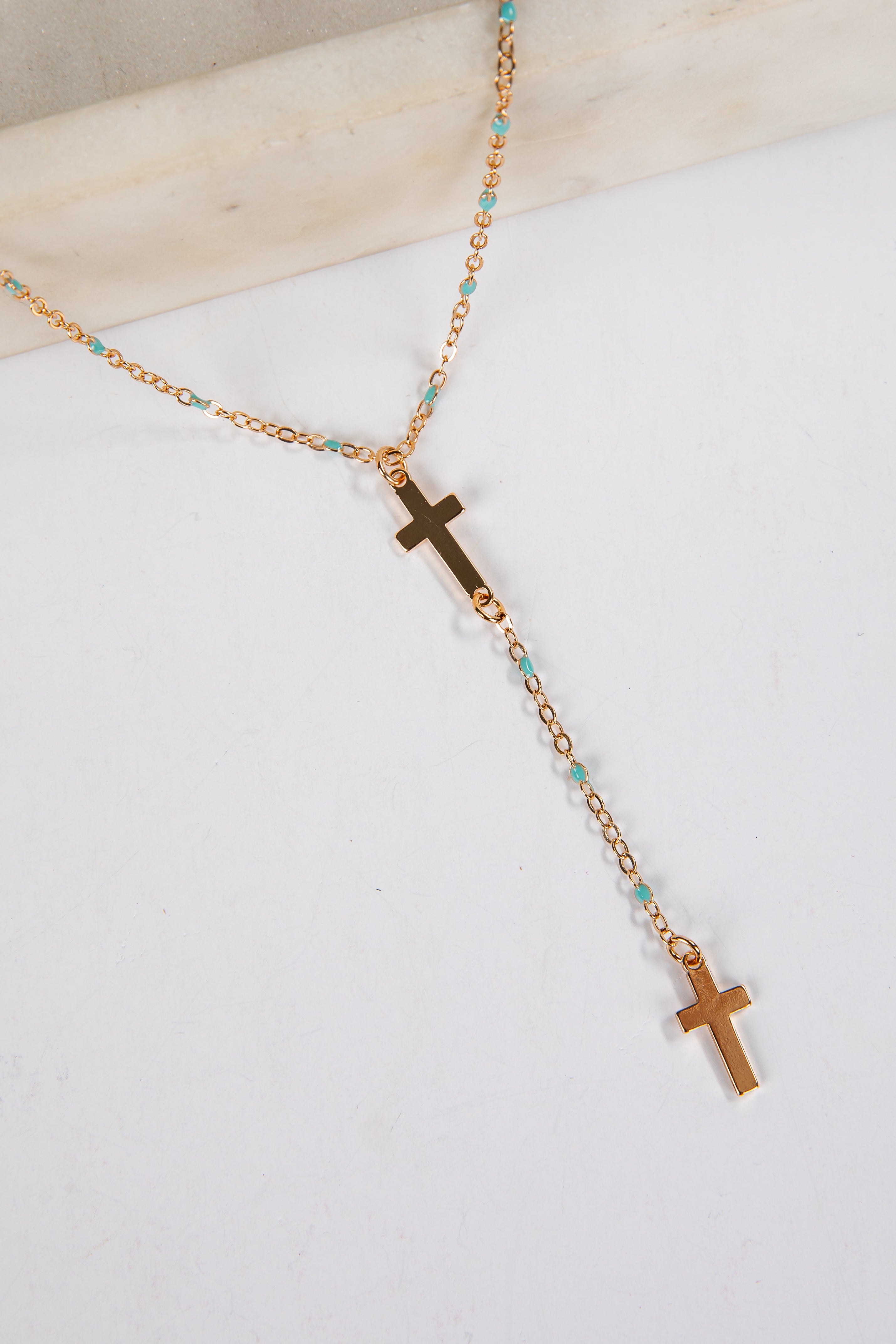 Necklace with gold crosses and turquoise beads on a white background