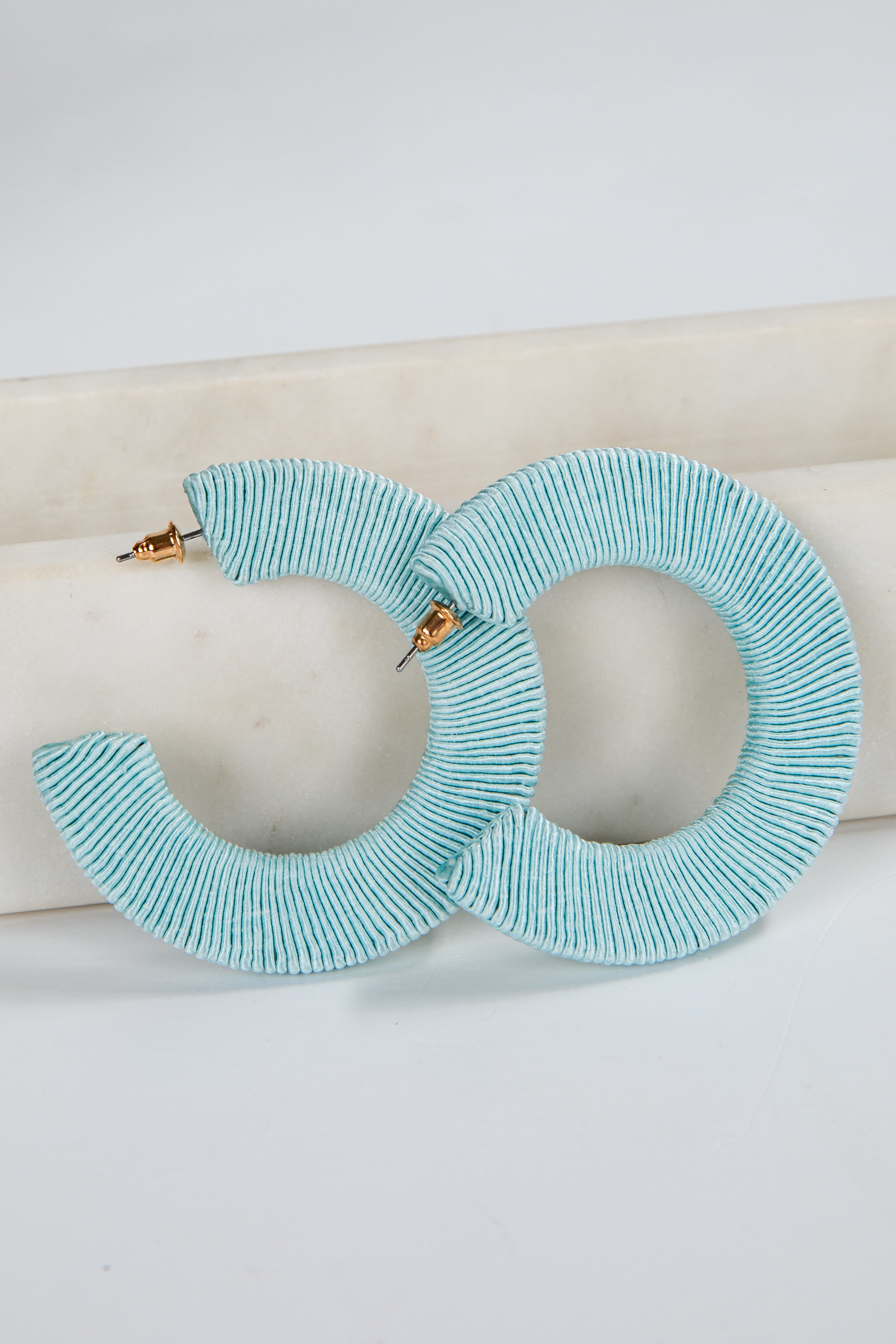 Turquoise hoop earrings on a white surface