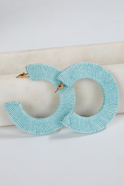 Turquoise hoop earrings on a white surface