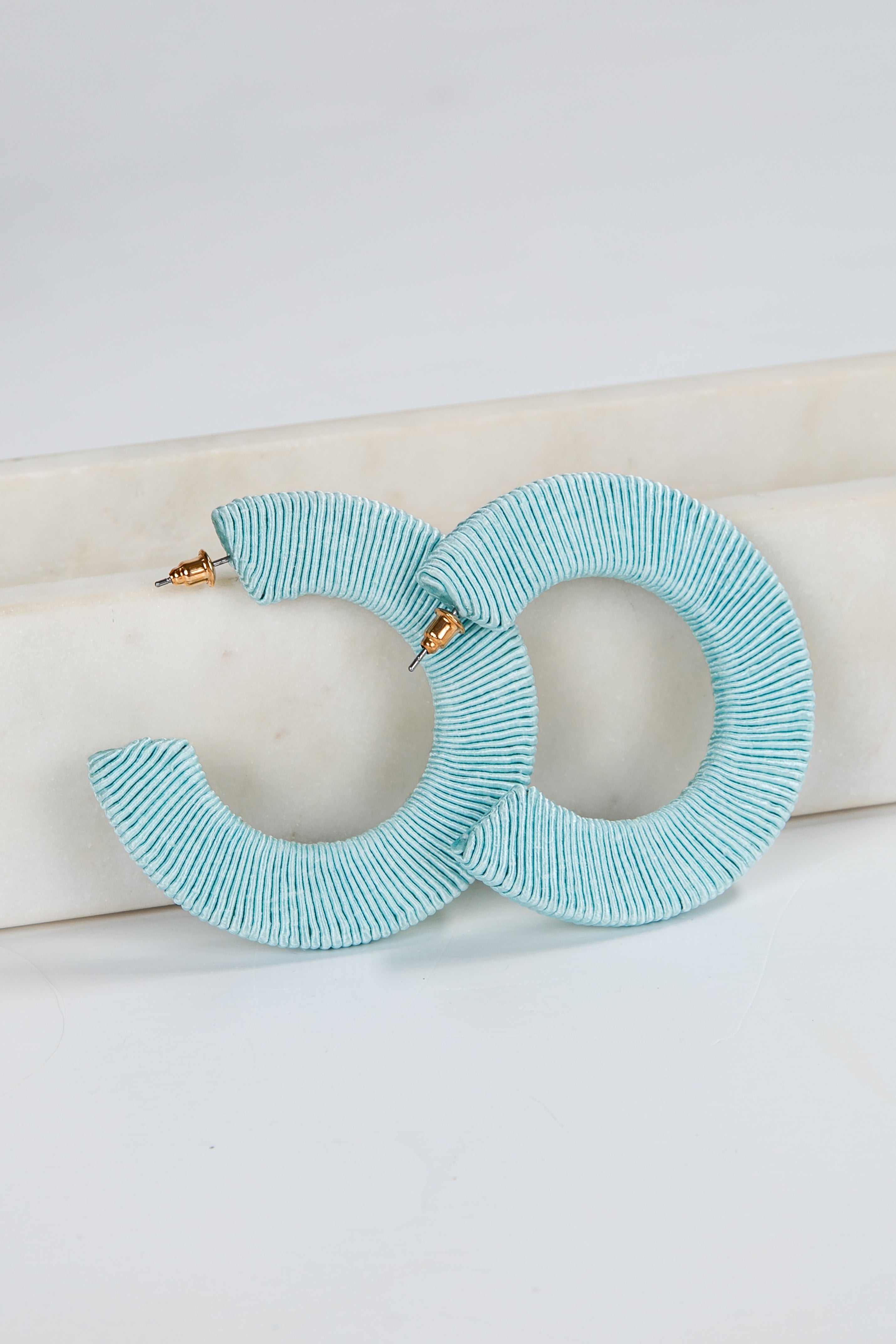 Pair of light blue hoop earrings on a white background