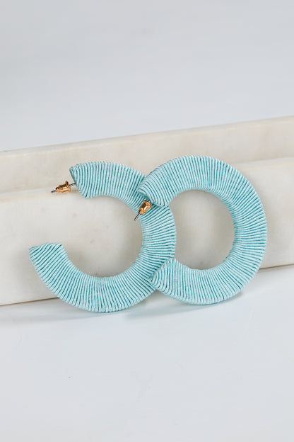 Pair of light blue hoop earrings on a white background