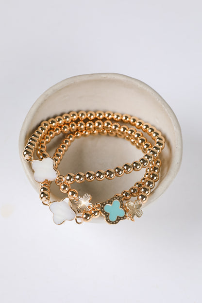 Gold bracelets with star-shaped charms on a white dish